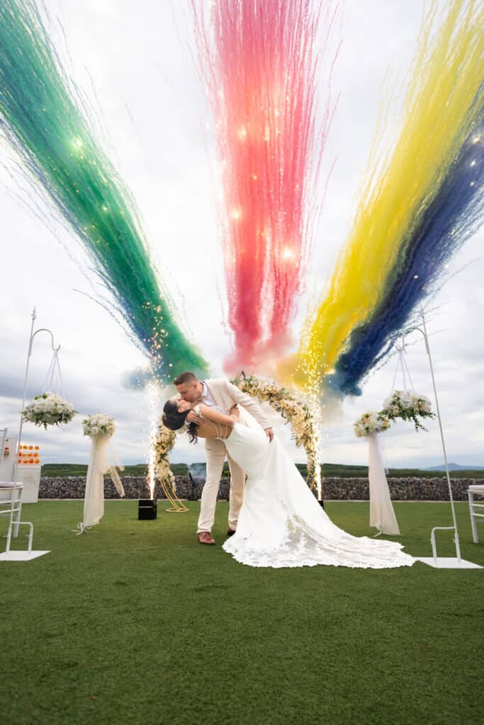 Tűzijáték teljes körű kivitelezése: moderne & spektakuläre feuerwerke an 1 ort 3 Ein Hochzeitspaar tanzt auf grünem Rasen, unter einem Blumenbogen, mit Feuerwerk im Hintergrund im Chateau Petrény.